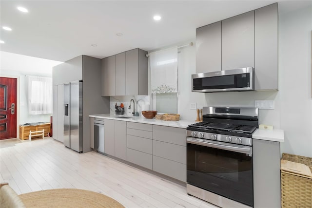 kitchen with light wood-style flooring, stainless steel appliances, light countertops, and gray cabinetry