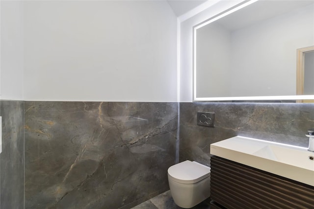 bathroom with vanity, toilet, and tile walls