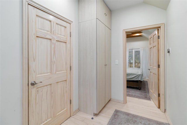 hallway with lofted ceiling and light wood-style floors