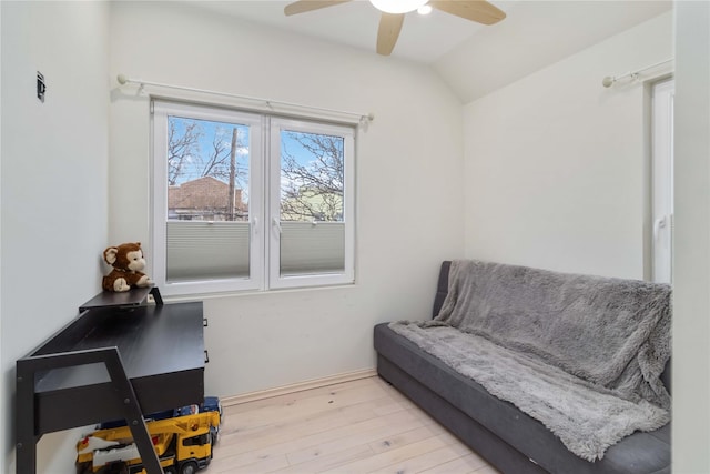 living area featuring ceiling fan, light wood-style flooring, and vaulted ceiling