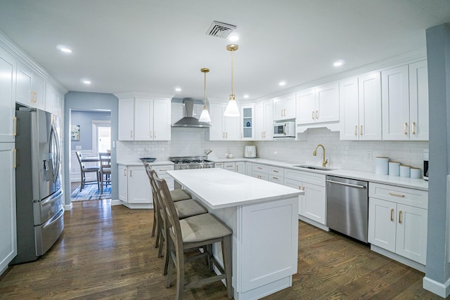 kitchen with a sink, visible vents, appliances with stainless steel finishes, dark wood-style floors, and wall chimney exhaust hood