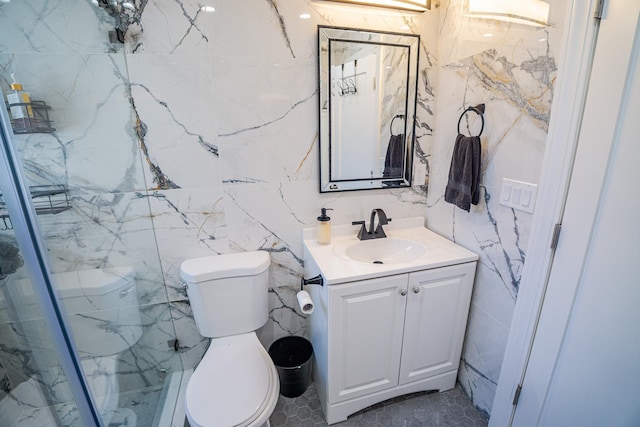 bathroom featuring toilet, a marble finish shower, and vanity