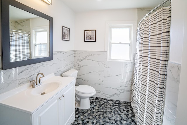 full bath with a wainscoted wall, a healthy amount of sunlight, vanity, and toilet