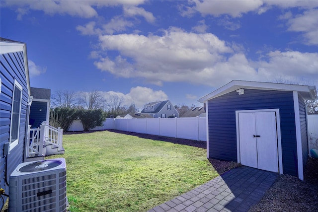 view of yard with a storage unit, central AC unit, an outbuilding, and a fenced backyard