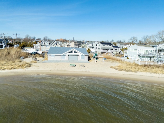 view of yard featuring a water view, a residential view, and a view of the beach