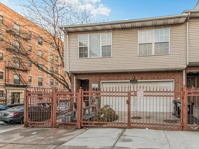 multi unit property featuring brick siding, a fenced front yard, and a gate