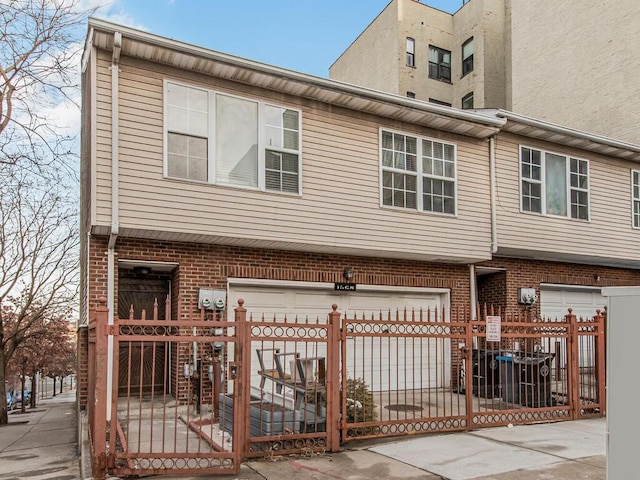 view of property featuring a fenced front yard, brick siding, and an attached garage