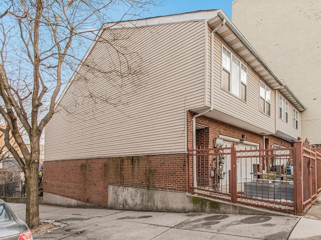 view of property exterior featuring fence and brick siding