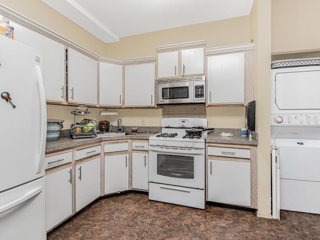 kitchen featuring light countertops, white appliances, stacked washer / dryer, and white cabinets