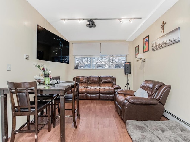 living room featuring a baseboard heating unit, rail lighting, and light wood-style flooring