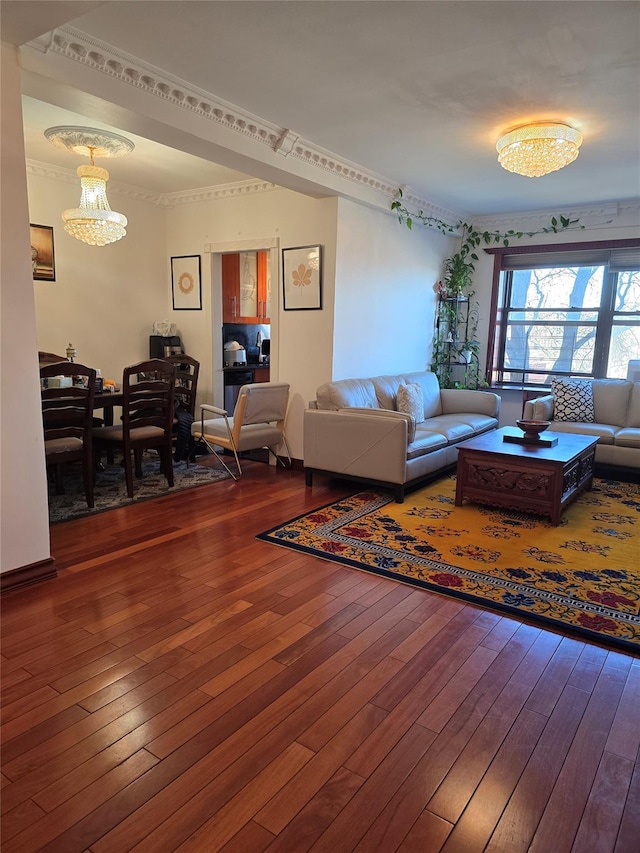 living area featuring crown molding, dark wood-type flooring, and a notable chandelier