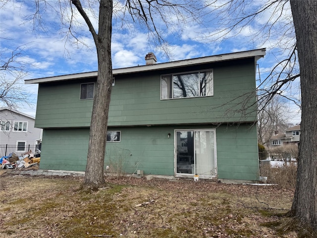 rear view of house with fence and a chimney