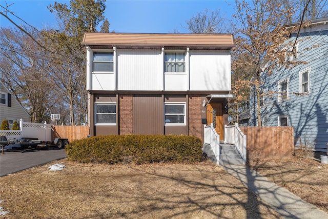 view of front of home featuring brick siding and fence