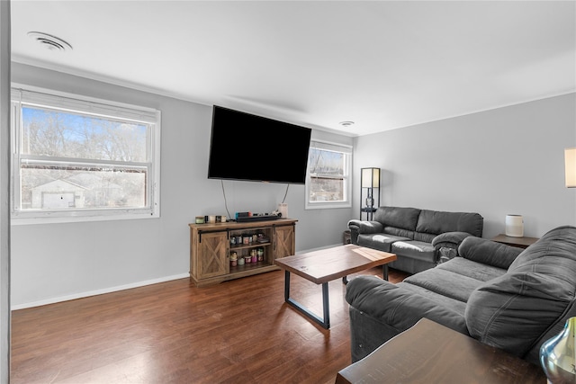 living area with wood finished floors, visible vents, and baseboards