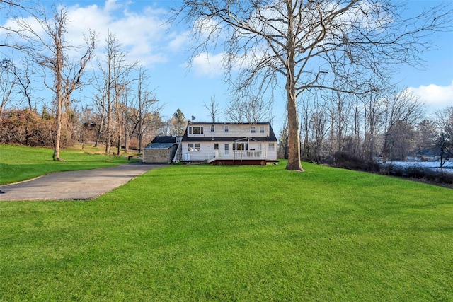 view of front of house with driveway, a deck, and a front yard