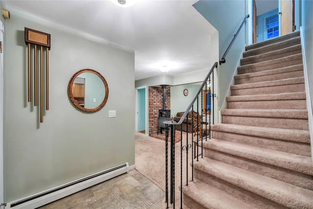 stairway featuring baseboards, baseboard heating, stone finish flooring, carpet, and a wood stove