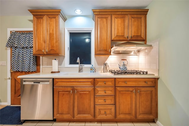 kitchen featuring appliances with stainless steel finishes, light countertops, backsplash, and exhaust hood