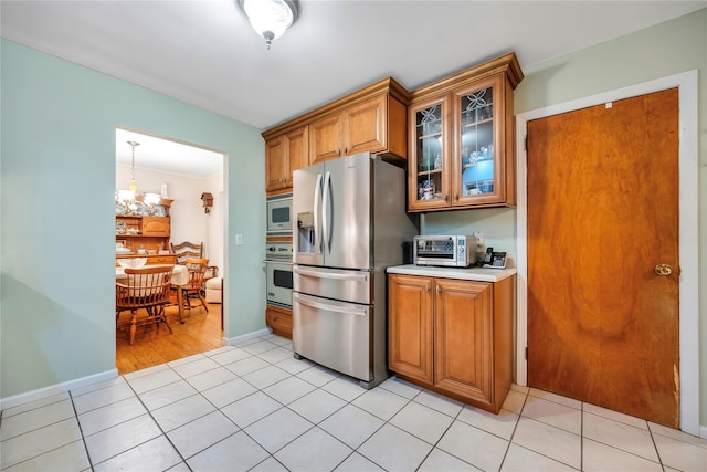 kitchen with brown cabinets, glass insert cabinets, stainless steel appliances, and light countertops