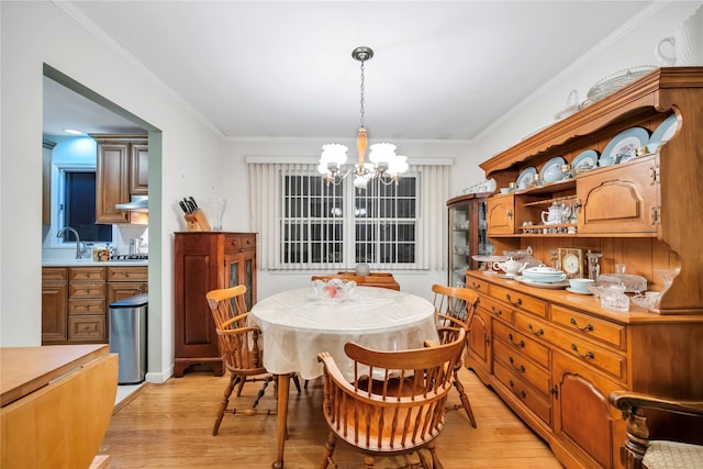 dining space with light wood-style floors, a chandelier, and crown molding