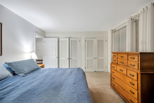 bedroom featuring two closets and light colored carpet