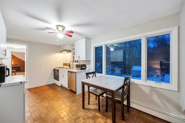 kitchen with a baseboard radiator, white range with gas cooktop, white cabinets, light countertops, and dishwasher