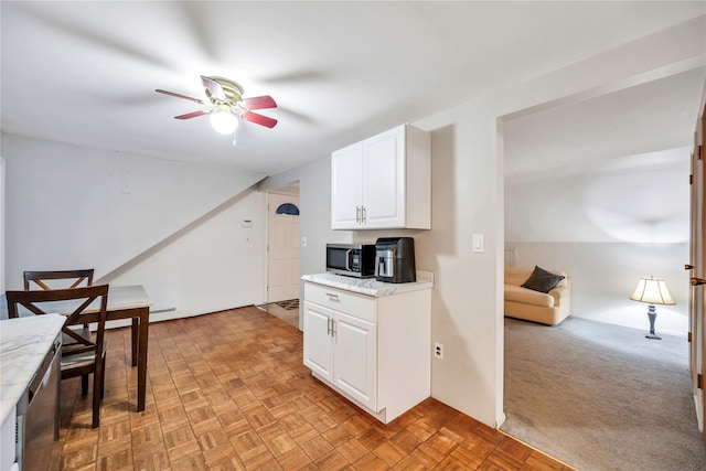 kitchen featuring a ceiling fan, light colored carpet, open floor plan, stainless steel appliances, and white cabinetry