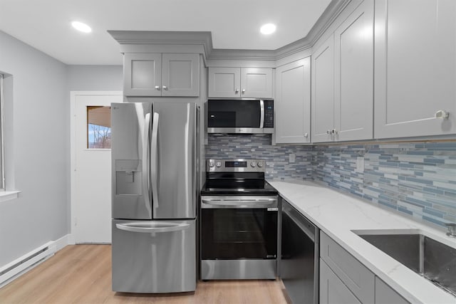 kitchen with light wood finished floors, baseboard heating, stainless steel appliances, gray cabinetry, and a sink