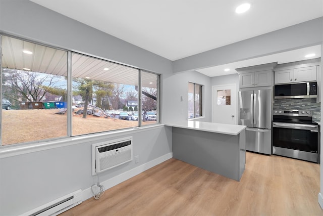 kitchen with stainless steel appliances, light wood-style floors, baseboard heating, a wall mounted AC, and gray cabinets