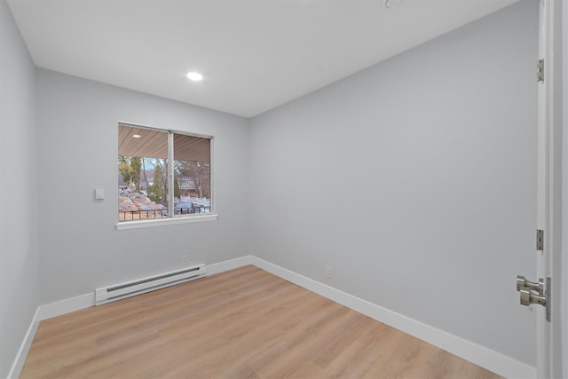 spare room featuring a baseboard heating unit, recessed lighting, light wood-type flooring, and baseboards