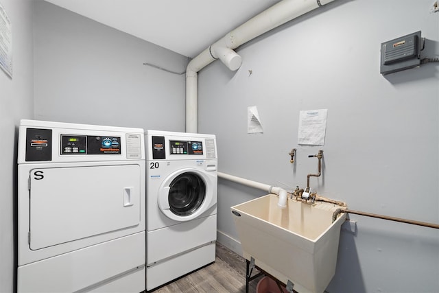 common laundry area with separate washer and dryer, a sink, and wood finished floors