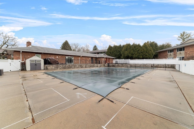 view of swimming pool with a storage shed, fence, a fenced in pool, and a patio