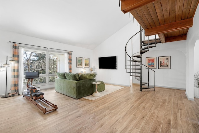 unfurnished living room with beam ceiling, stairway, light wood-type flooring, and baseboards