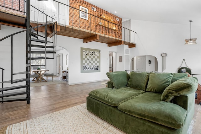 living area featuring wood finished floors, baseboards, arched walkways, stairs, and a towering ceiling