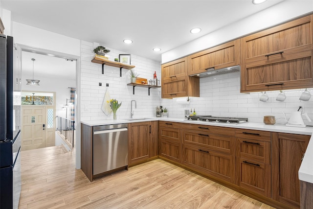 kitchen with a sink, stainless steel appliances, light wood finished floors, and light countertops