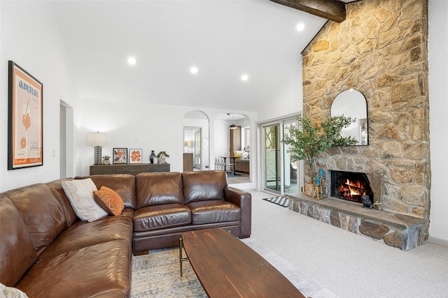 carpeted living room featuring beamed ceiling, high vaulted ceiling, recessed lighting, arched walkways, and a stone fireplace