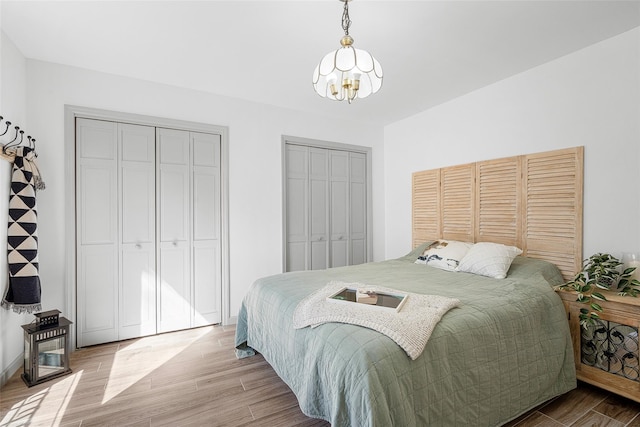 bedroom with wood finished floors, multiple closets, and a chandelier