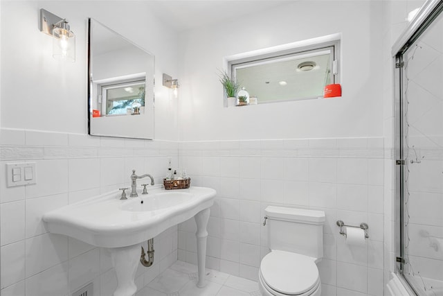 bathroom featuring wainscoting, toilet, and tile walls