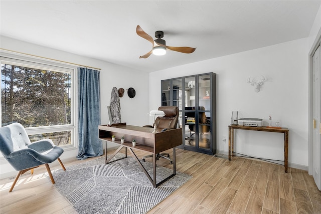 office featuring baseboards, light wood-style floors, and ceiling fan