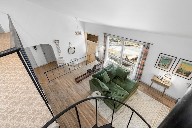 living area featuring wood finished floors, baseboards, and high vaulted ceiling