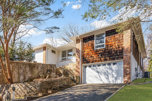 view of front of property with stucco siding, driveway, central AC, an attached garage, and stairs