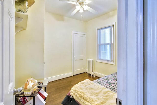 bedroom featuring baseboards, dark wood-type flooring, a ceiling fan, and radiator