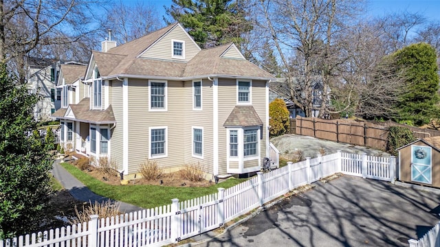 view of side of property with a fenced backyard, driveway, and a chimney