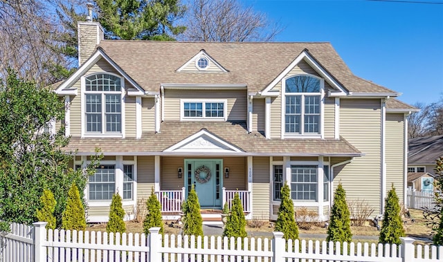 view of front of home featuring covered porch, a fenced front yard, and a chimney