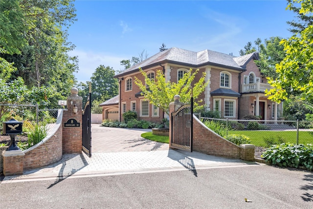 view of front of property with a fenced front yard, decorative driveway, brick siding, and a gate