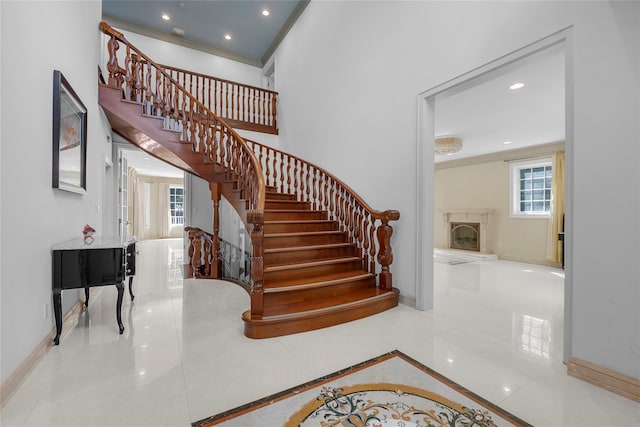 stairway with a fireplace, baseboards, crown molding, and recessed lighting