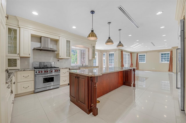 kitchen with wall chimney range hood, luxury range, backsplash, and light tile patterned flooring