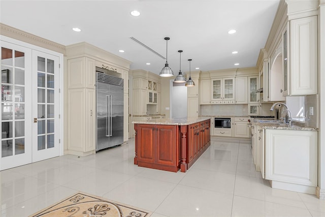 kitchen featuring light tile patterned floors, decorative backsplash, light stone counters, glass insert cabinets, and stainless steel built in refrigerator