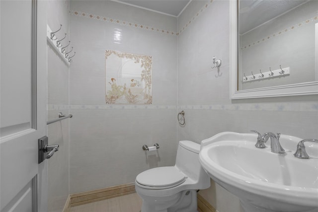 bathroom featuring a sink, tile walls, and toilet