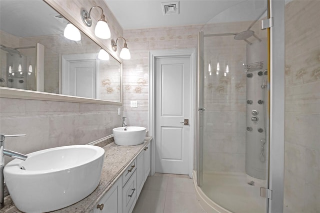 bathroom featuring tile walls, visible vents, a stall shower, a sink, and tile patterned flooring