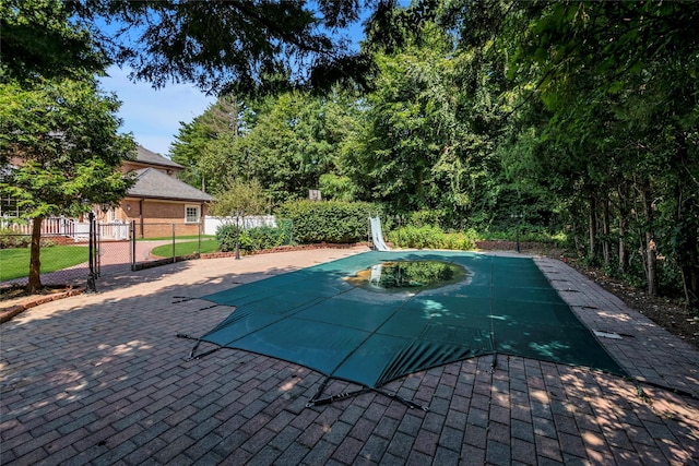 view of swimming pool featuring a patio area, a fenced in pool, fence, and a water slide